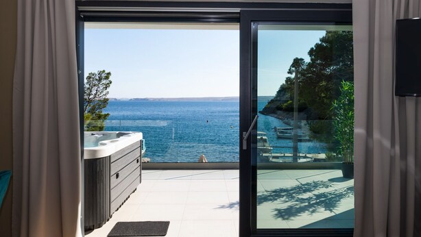 Ein Balkon mit Meerblick, einem Whirlpool und einer kleinen Sitzecke im Freien.