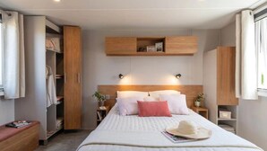 Une chambre bien rangée, avec un lit, des tables de chevet, une armoire et des étagères intégrées.