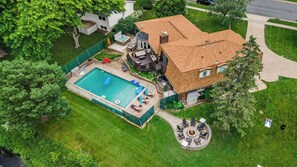 Eine Vogelperspektive eines Hauses mit Swimmingpool, Whirlpool und einem runden Sitzbereich im Freien.