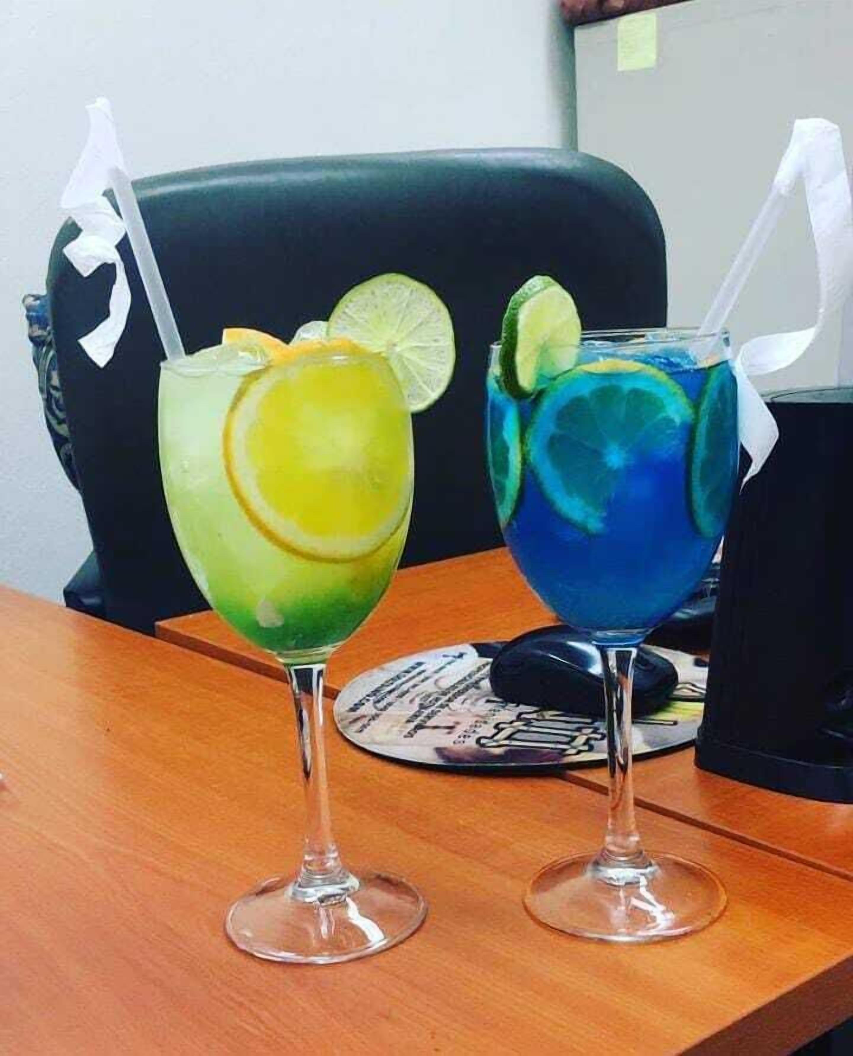 Dos vasos de bebidas sobre una mesa de madera, con una silla negra al fondo.