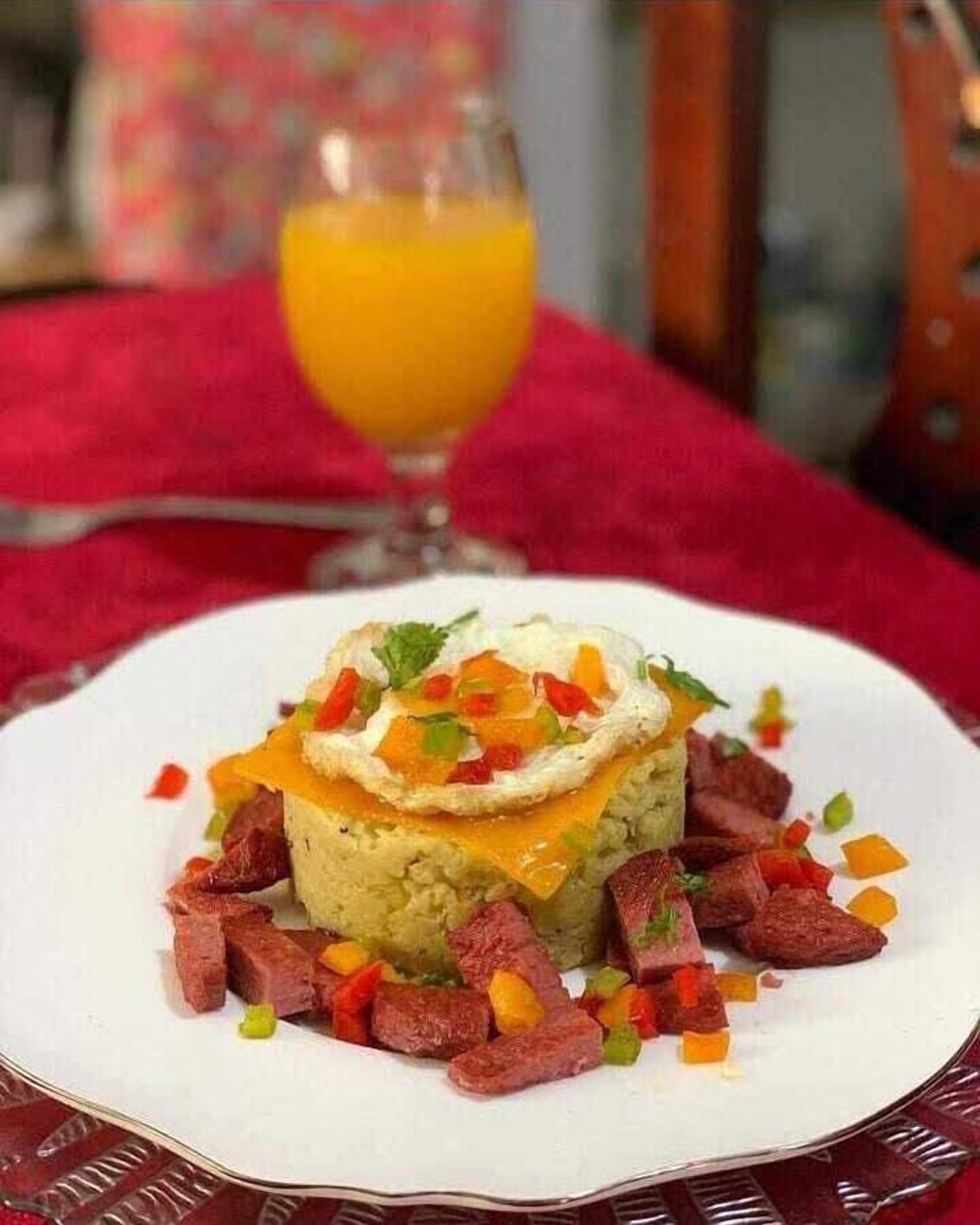 Une assiette de nourriture contenant un plat en couches, peut-être un gratin, recouvert de fromage et garni d’herbes.