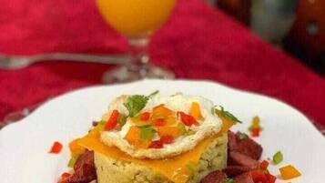 Une assiette de nourriture contenant un plat en couches, peut-être un gratin, recouvert de fromage et garni d’herbes.