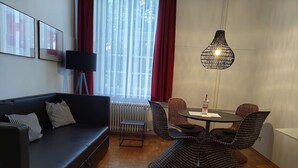 A modern living room with a sofa, a dining table with chairs, a lamp, and a radiator. - Central One-Bedroom Apartment in Konstanz (Konstanz)