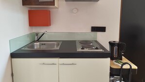 A compact kitchen with a sink, stove, and a coffee maker. - Central One-Bedroom Apartment in Konstanz (Konstanz)
