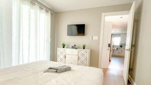 A bedroom with a bed, a dresser, a TV, and a view into the kitchen. - Exotic home Rogers by sdstay (Casa de Oro-Mount Helix)