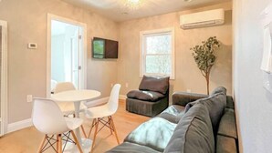 A living room with a sofa, a dining table with chairs, a TV mounted on the wall, and a window with a view. - Exotic home Rogers by sdstay (Casa de Oro-Mount Helix)