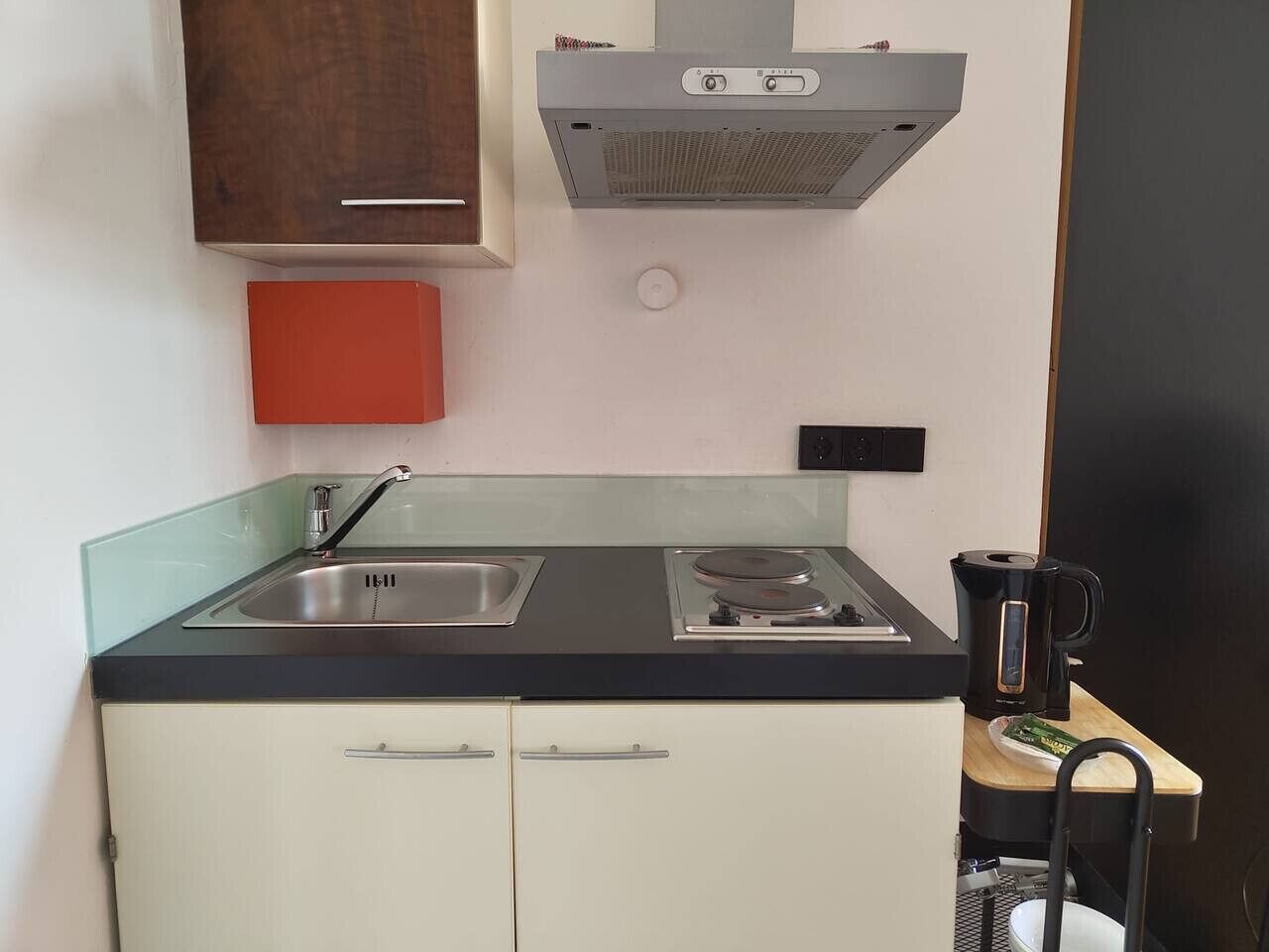 A compact kitchen with a sink, stove, and a coffee maker on the counter.