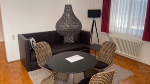 A modern living room with a dark sofa, a round black table, and wicker chairs. - Central One-Bedroom Apartment in Konstanz (Konstanz)