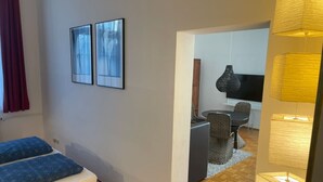 A room with a bed, a small table, and a chair. There are two framed pictures on the wall. - Central One-Bedroom Apartment in Konstanz (Konstanz)