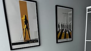 Ein graues Sofa mit zwei gelben Kissen und zwei gerahmten Kunstwerken an der Wand.