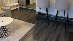 Eine moderne Küche mit integriertem Kühlschrank, einem Essbereich mit zwei Barhocker und einer kleinen Sitzecke mit rundem Tisch und Stuhl.