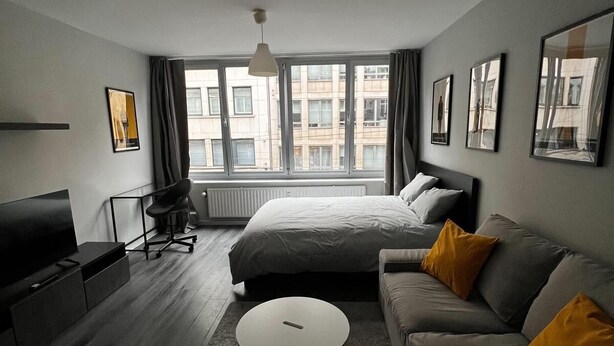 Ein modernes Hotelzimmer mit einem großen Bett, einer Couch, einem Fernseher und einem Schreibtisch.