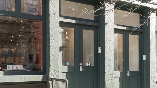 A building with two green doors, a visible number '303', and a 'OPEN' sign on the window. - Olde City Loft Style Condo (Philadelphia)