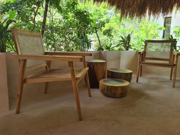 A wooden chair with a woven backrest and seat, placed on a concrete floor with a backdrop of lush green foliage. - Private Pool and Jacuzzi Penthouse S6 (Tulum)