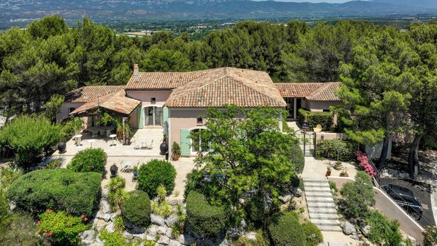 A villa with a tiled roof, surrounded by lush greenery and a mountainous backdrop. - La Villa Kef (Mallemort)