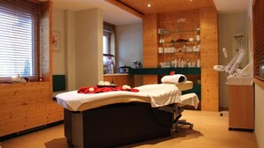 Un cuarto de spa con una camilla de masaje, un estante con botellas y techo de madera.
