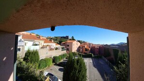 Blick durch ein Fenster auf ein Wohngebiet mit Gebäuden, einem Parkplatz und blauem Himmel.