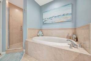Ein Badezimmer mit einer Badewanne, einer Dusche und einem Meeresblick-Gemälde an der Wand.