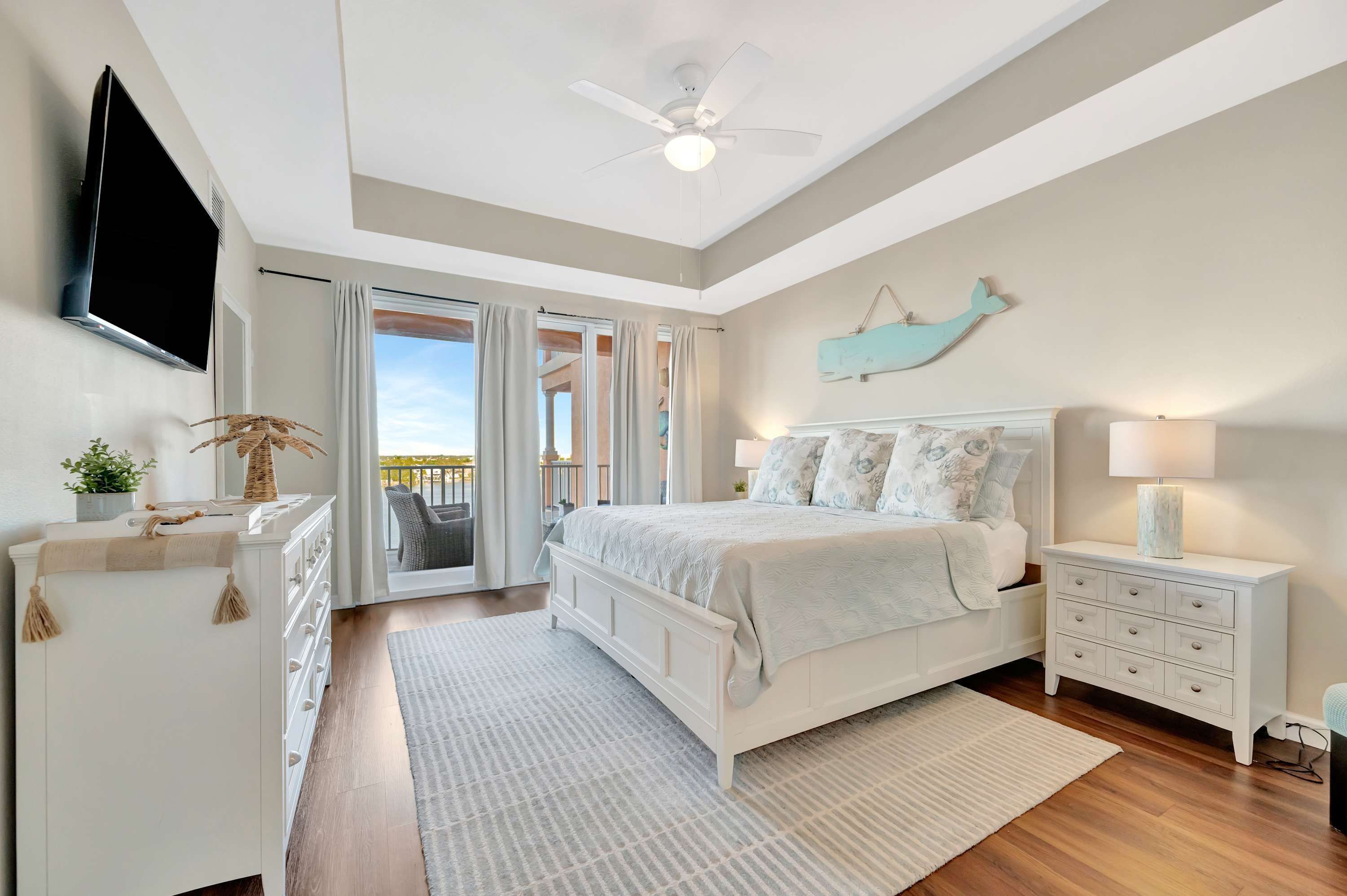 A bedroom with a bed, nightstand, TV, and a view of the outdoors.