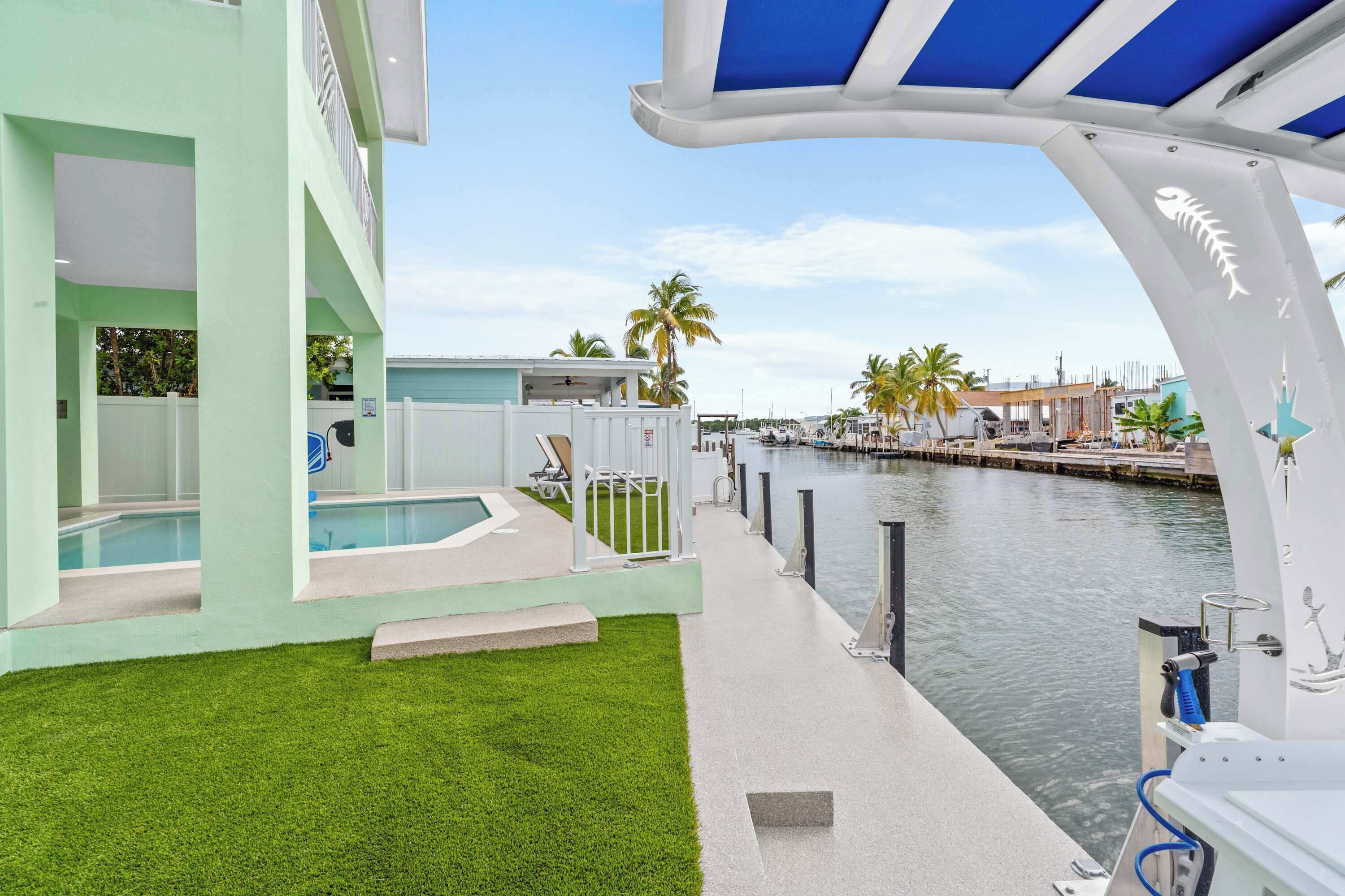 A modern building with a pool, a covered patio, and a view of the marina.