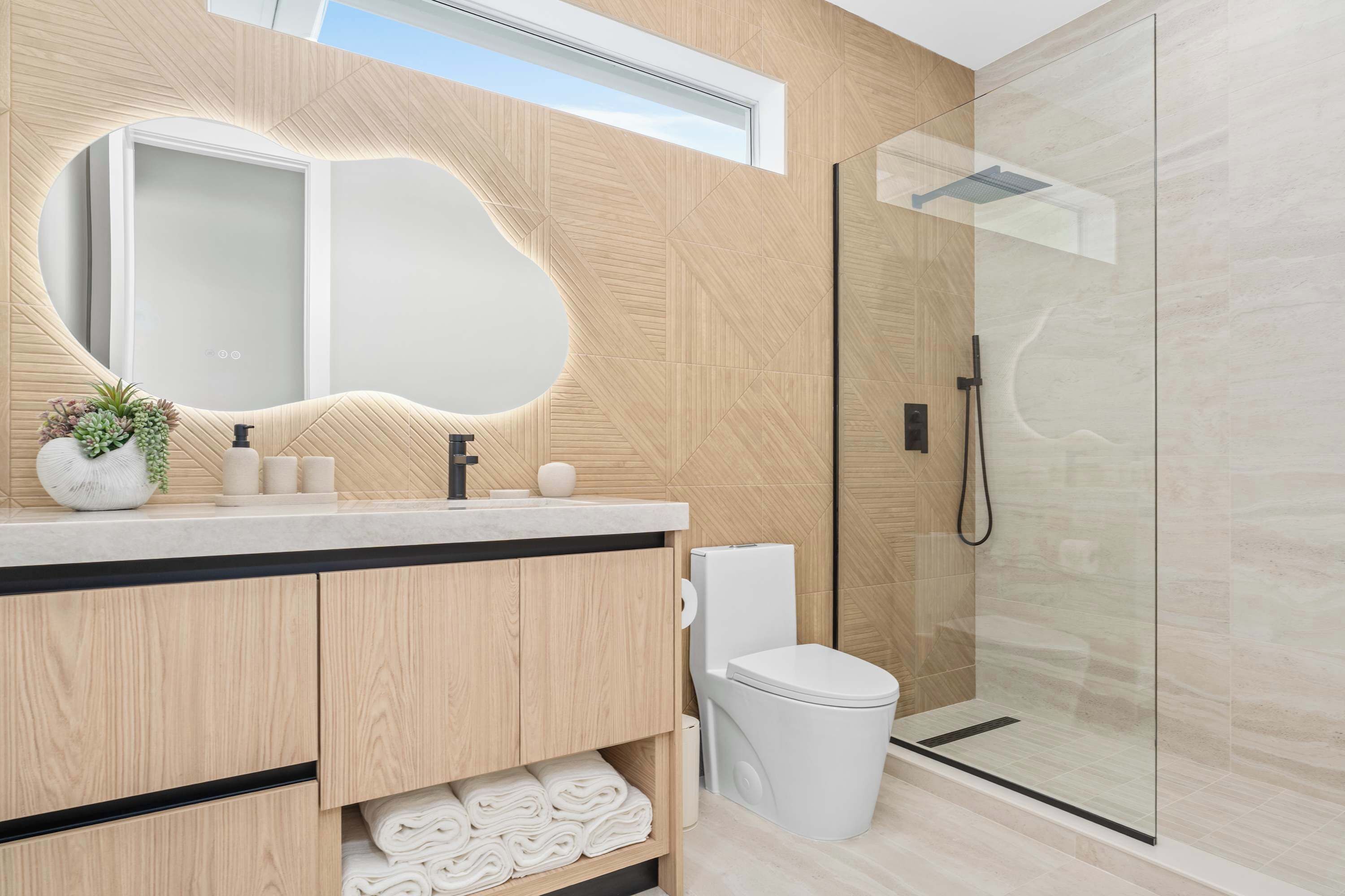 Une salle de bain moderne avec un meuble-lavabo en bois, un grand miroir, une douche en verre et des toilettes.