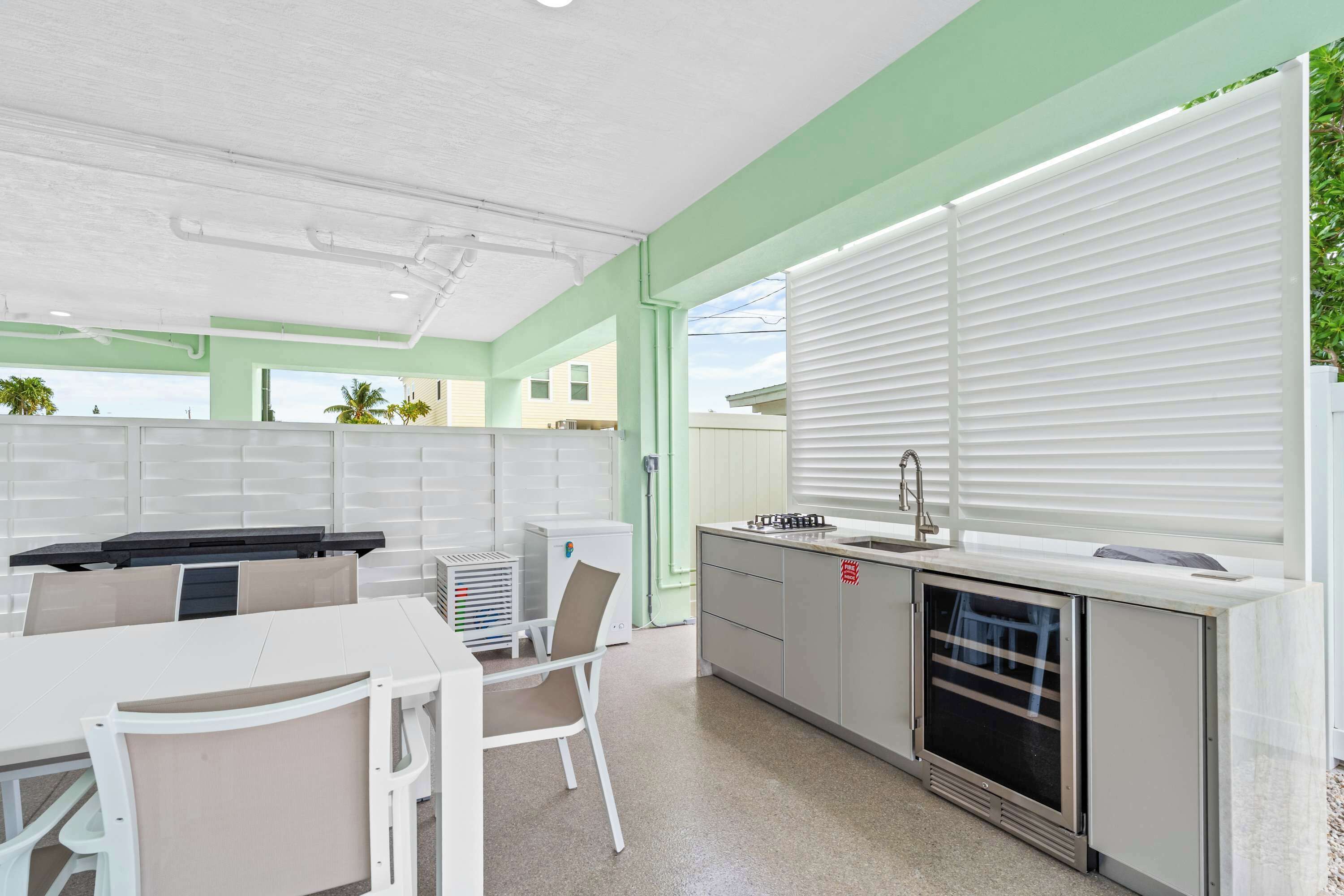A modern kitchen with white cabinets, a built-in oven, and a window with blinds.