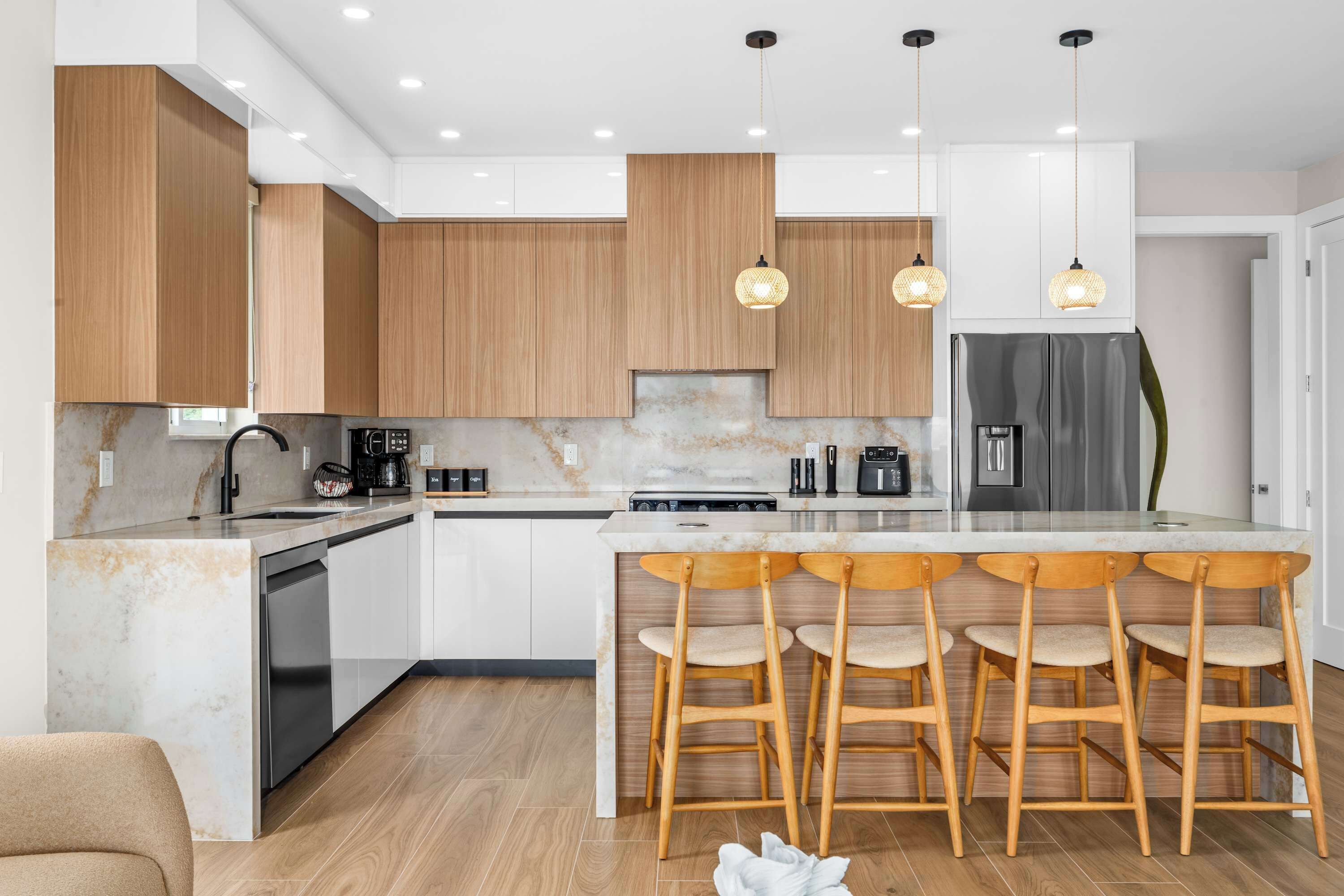Una cucina moderna con mobili in legno, un piano di lavoro in marmo e un frigorifero in acciaio inossidabile.