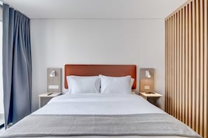 A hotel room with a large bed, two bedside tables with lamps, a wooden headboard, and a striped wall panel. - w Awesome Loft w Balcony in Santa Barbara (Bogotá)