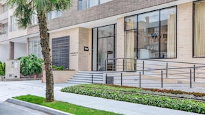 A modern building with a glass entrance, a staircase leading to the entrance, and a well-maintained garden area. - w Gorgeous 2BR w Balcony in Santa Barbara (Bogotá)