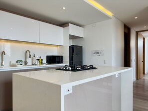 A modern kitchen with white cabinetry, a central island, a built-in microwave, and a gas stove. - w Gorgeous 2BR w Balcony in Santa Barbara (Bogotá)