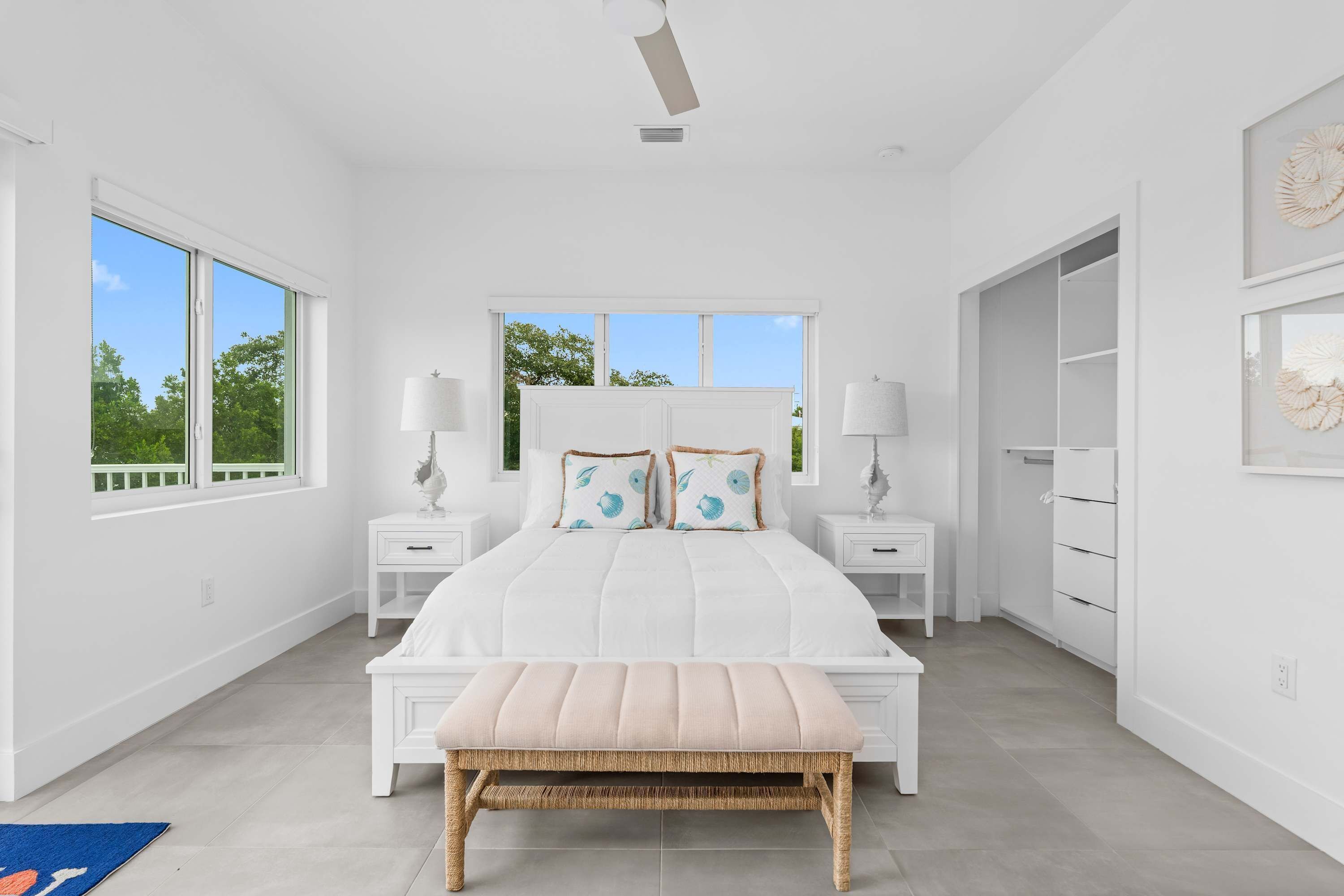A bedroom with a large bed, two bedside tables, a bench, and a wardrobe.
