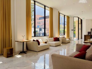 A modern hotel lobby with large windows, a seating area with sofas, and a small table with a vase. - w Heavenly Loft w Balcony in Santa Barbara (Bogotá)