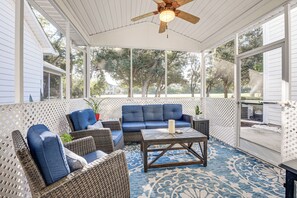 A covered patio area with wicker furniture, a blue sofa, and a coffee table. - Golf Getaway w/ Resort Perks in North Myrtle Beach (North Myrtle Beach)