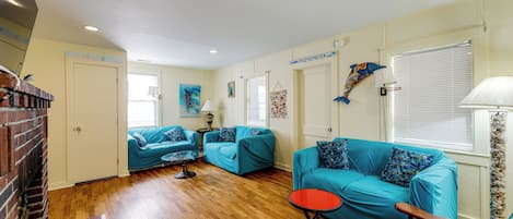 A living room with a wooden floor, a blue sofa set, a red coffee table, and a striped armchair.