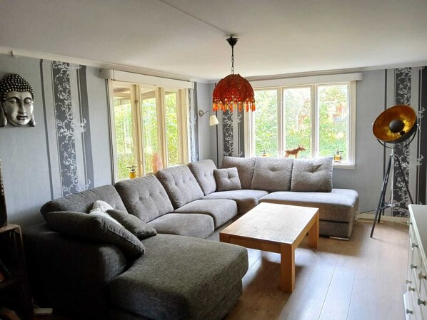 Una sala moderna con un sofá seccional gris, una mesa de centro de madera y una lámpara de pie.