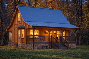 Eine Holzhütte mit Veranda, Stein Fundament und einem Metalldach.