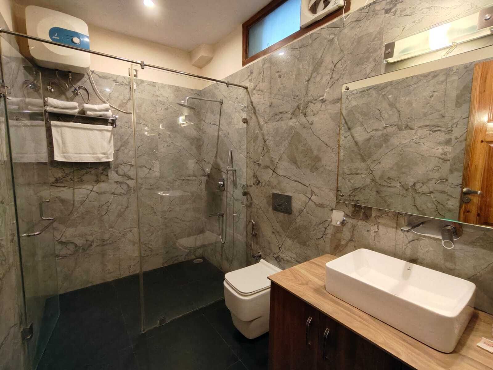 Un baño moderno con ducha de vidrio, inodoro blanco y tocador de madera con un lavamanos grande.