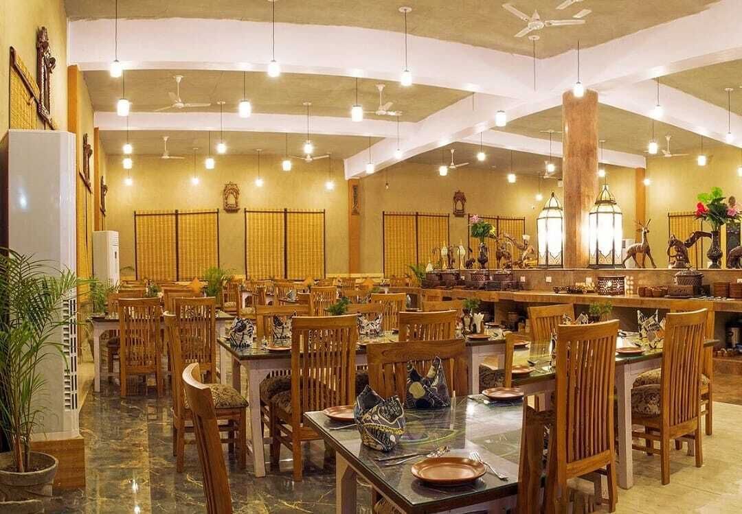 A spacious dining area with multiple tables and chairs, ceiling fans, and decorative lanterns.
