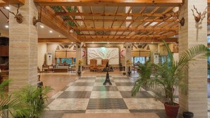 A spacious lobby with a checkered floor, wooden ceiling beams, and a central seating area. - The Banyan Retreat by Excel Hotels & Resorts (Ramnagar)