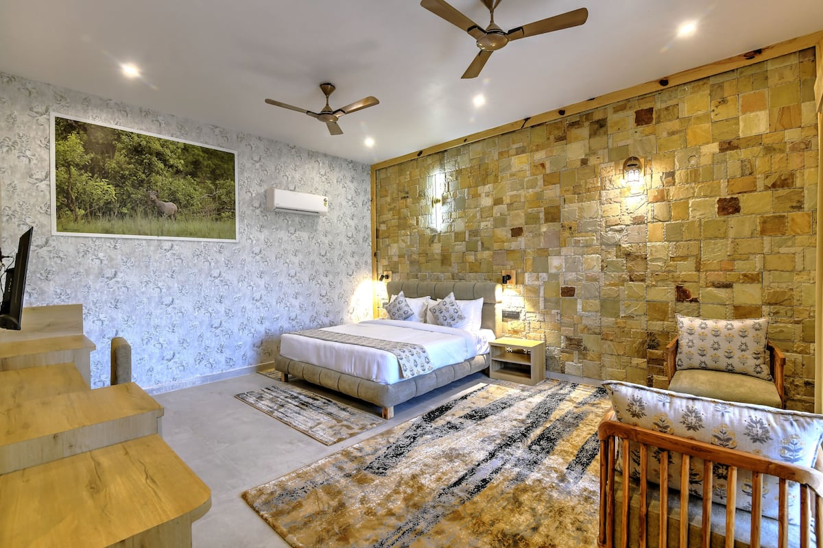 A bedroom with a bed, two nightstands, a chair, a wooden staircase, and a large wall mural.