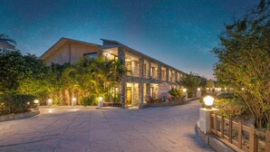 Un hotel con fachada de piedra, varios balcones y un cielo estrellado.