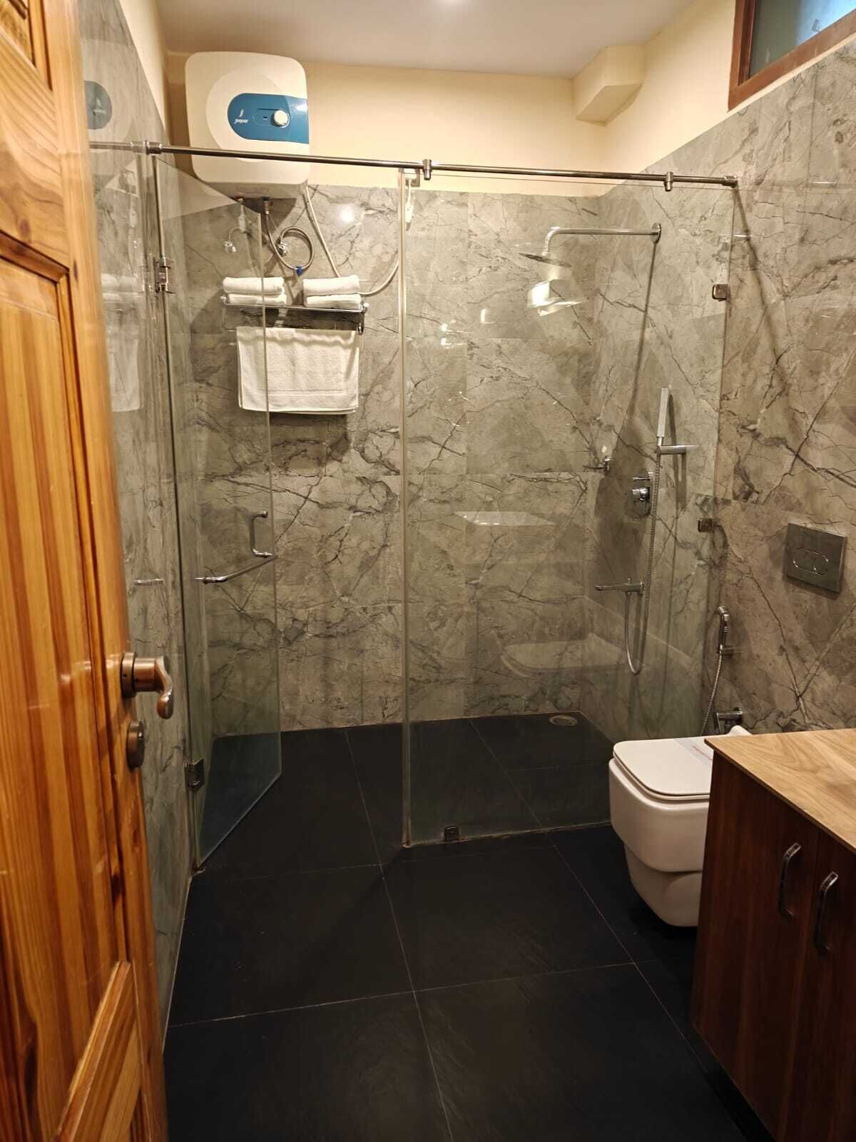 Ducha con cerramiento de vidrio, inodoro y armario de madera.