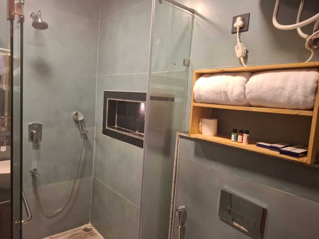 A shower area with a glass door, a towel shelf, and a small window.