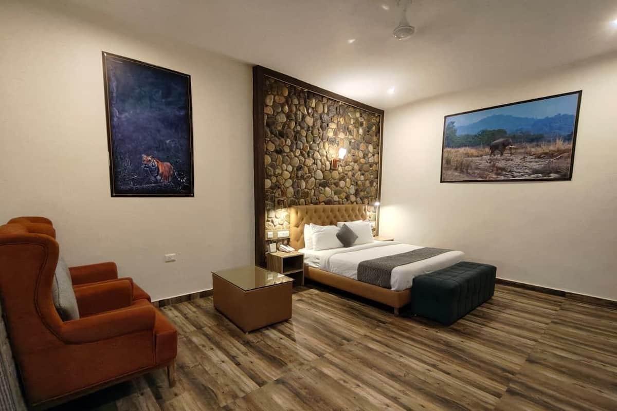 A bedroom with a bed, a nightstand, a chair, a coffee table, and two paintings on the walls.