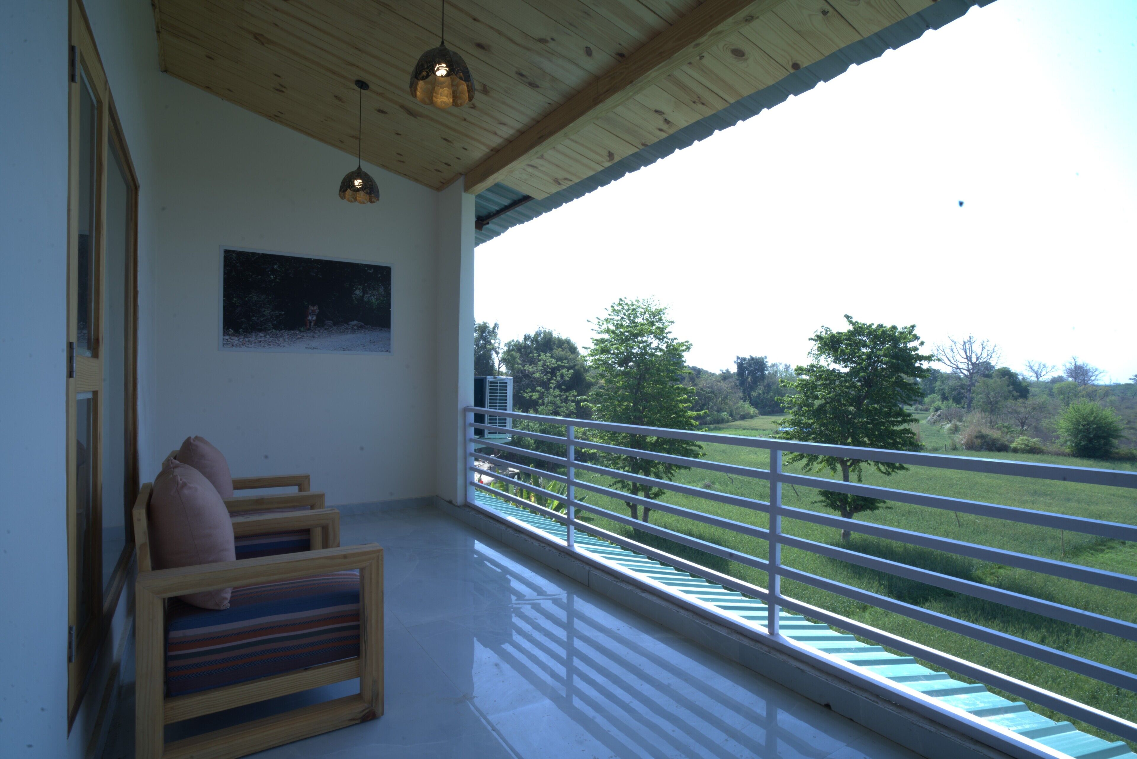 Een balkon met houten vloer, een leuning en uitzicht op een groen landschap.
