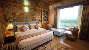 Un dormitorio con pared de piedra, una cama, una silla, una mesa y una ventana con vistas.