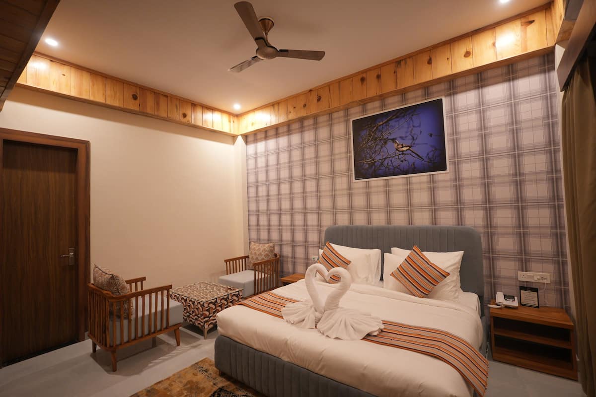 A bedroom with a bed, a crib, a nightstand, a ceiling fan, and a wall-mounted picture.
