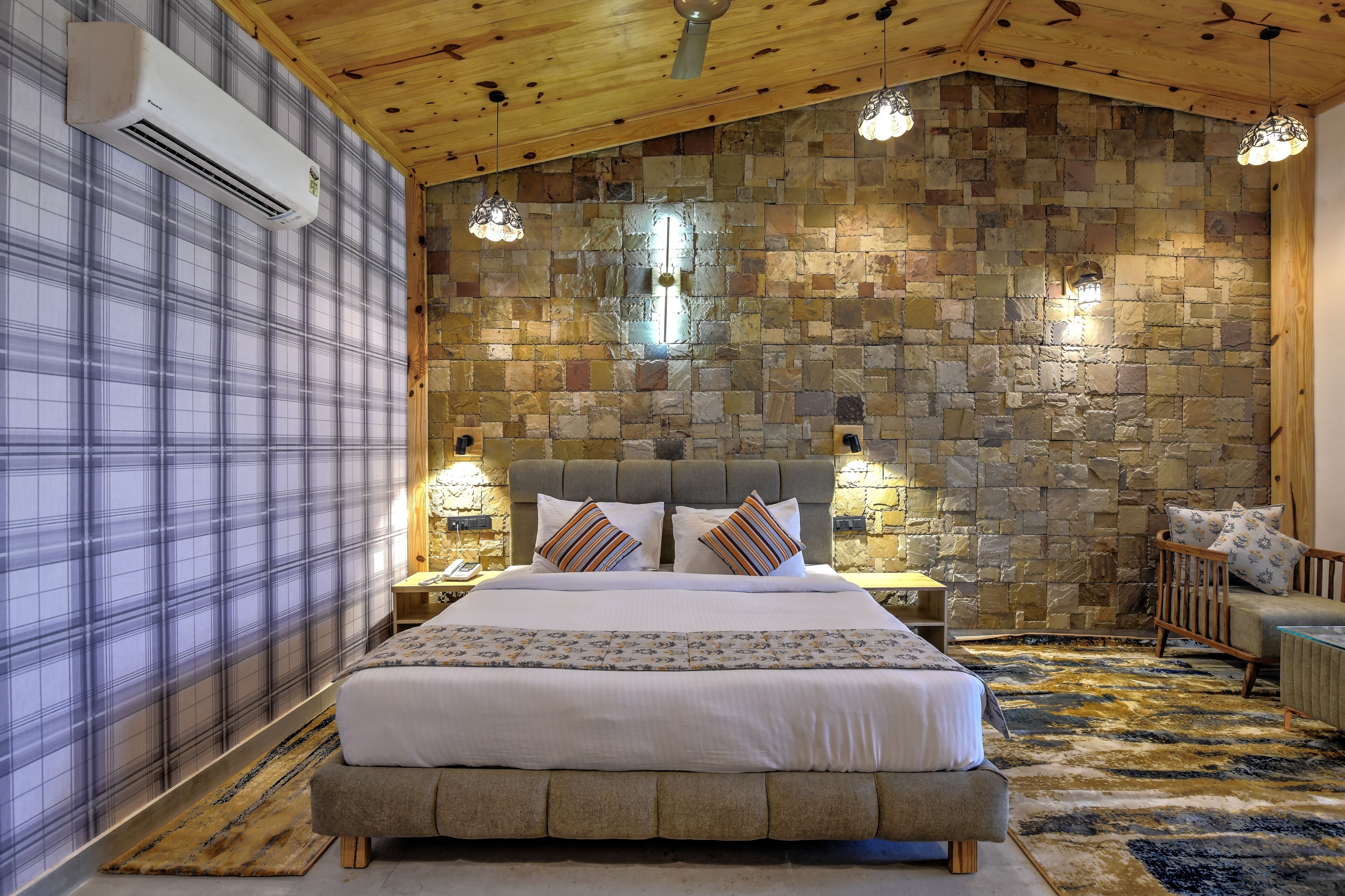Una camera da letto con un letto grande, un muro in pietra, un soffitto in legno e una parete a motivi tartan.
