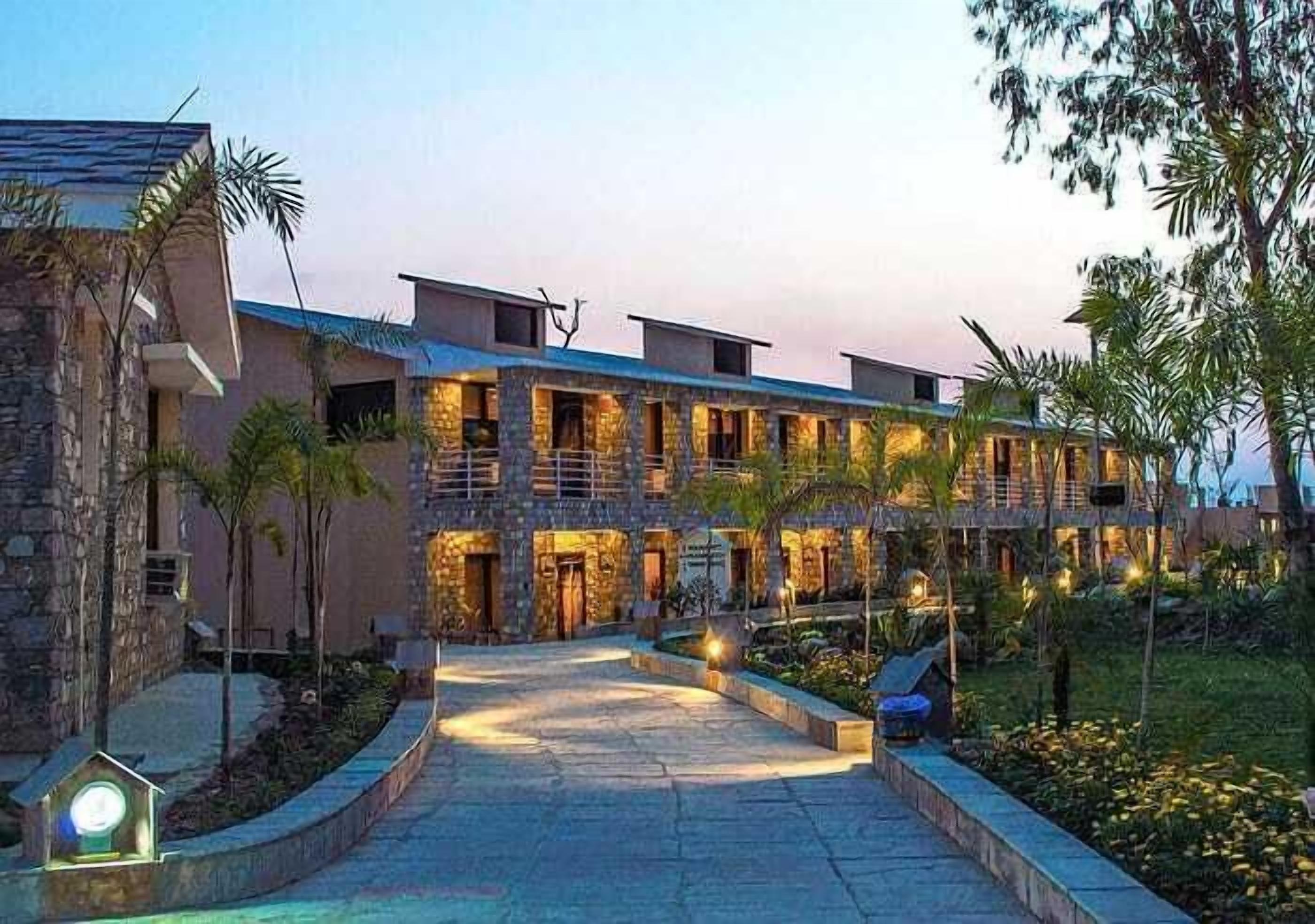 A multi-story hotel with a stone facade, a central courtyard, and outdoor lighting.