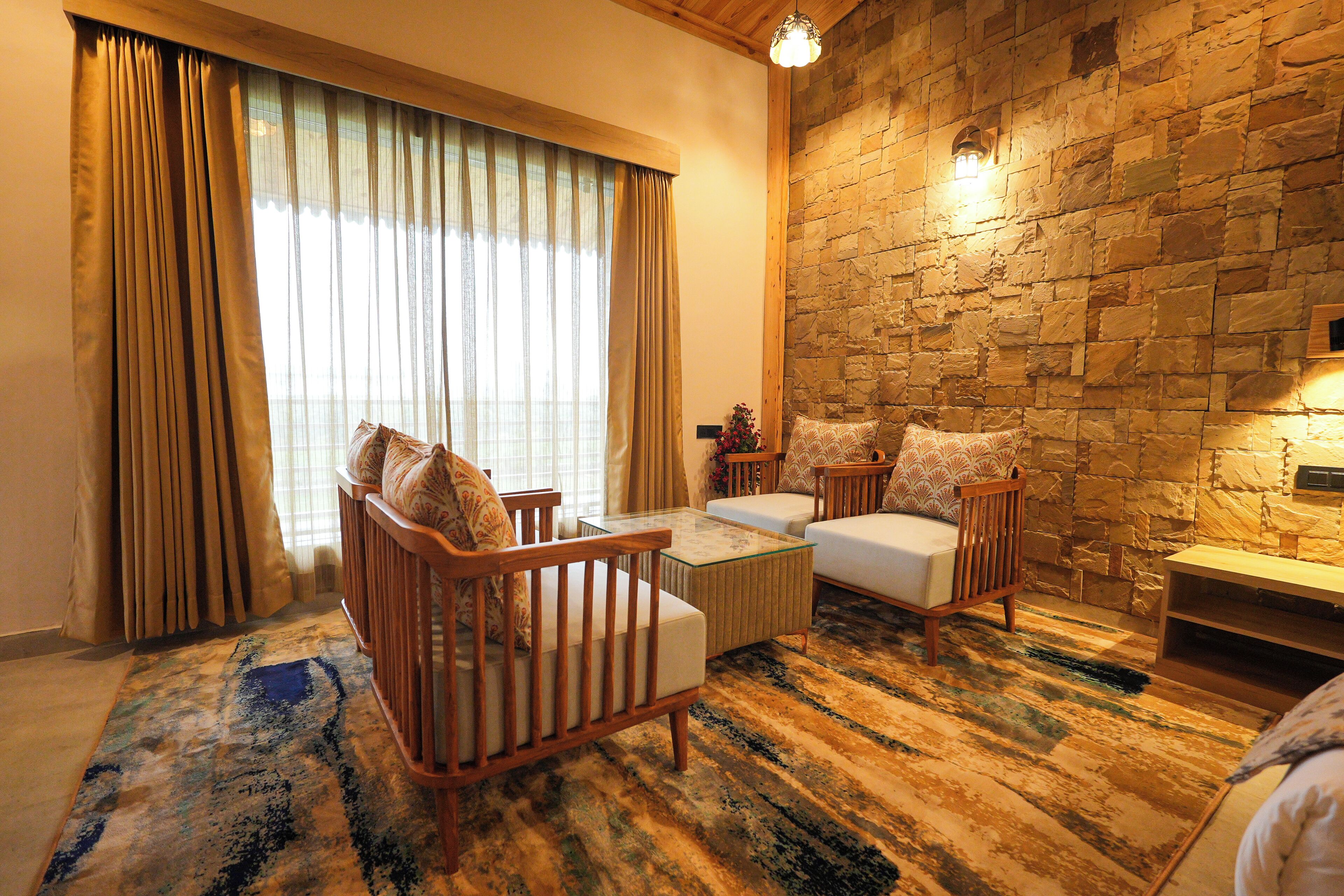 Una habitación con pared de piedra, un sofá, una silla, una mesita de centro y una lámpara.